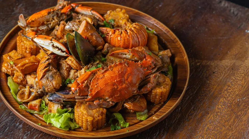 Seafood Bake with crab, lobster tail, mussels and corn on a wooden platter